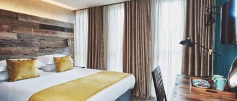Ein Hotelzimmer mit Bett, Schreibtisch, Sessel und Fernseher.
