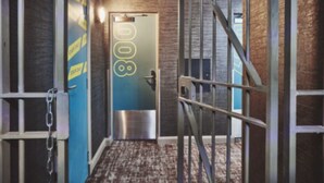 Un pasillo con una escalera de metal, una puerta con un número y una pared con cinta amarilla.