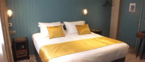 A hotel room with a large bed, two bedside tables, and a wardrobe.
