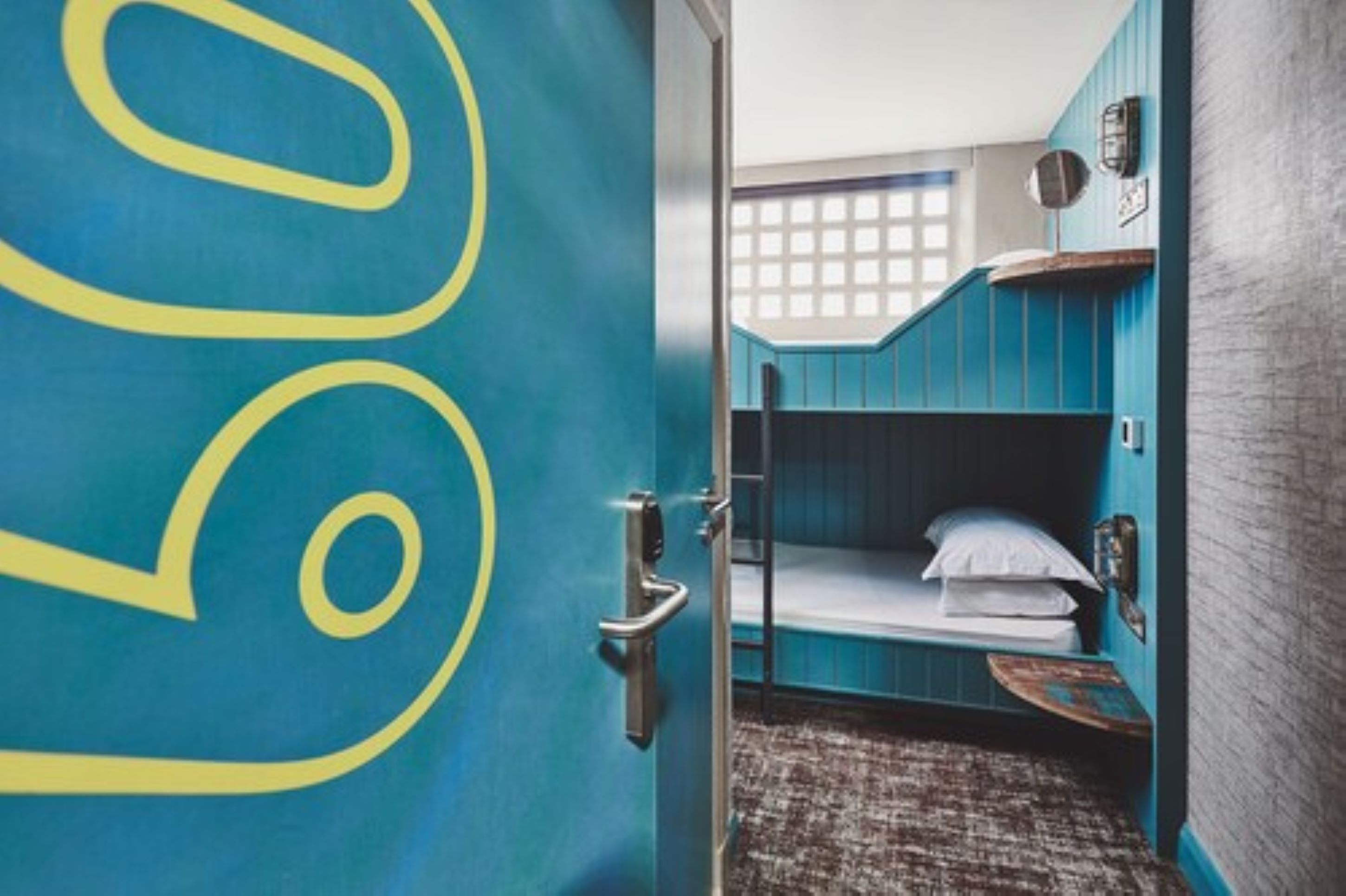 A room with bunk beds, a small table, and a window with a grid pattern.