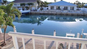 A waterfront property with a pool, a boat dock, and a house with a blue roof. - Knee Deep in the Water Somewhere... (Key Colony Beach)