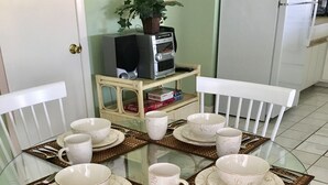 A round glass table with white chairs, each with a patterned cushion. - Knee Deep in the Water Somewhere... (Key Colony Beach)