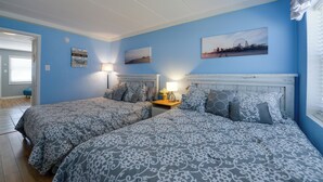 Ein Schlafzimmer mit zwei Betten, einem Nachttisch, einer Lampe und einer Wand mit maritimer Dekoration.