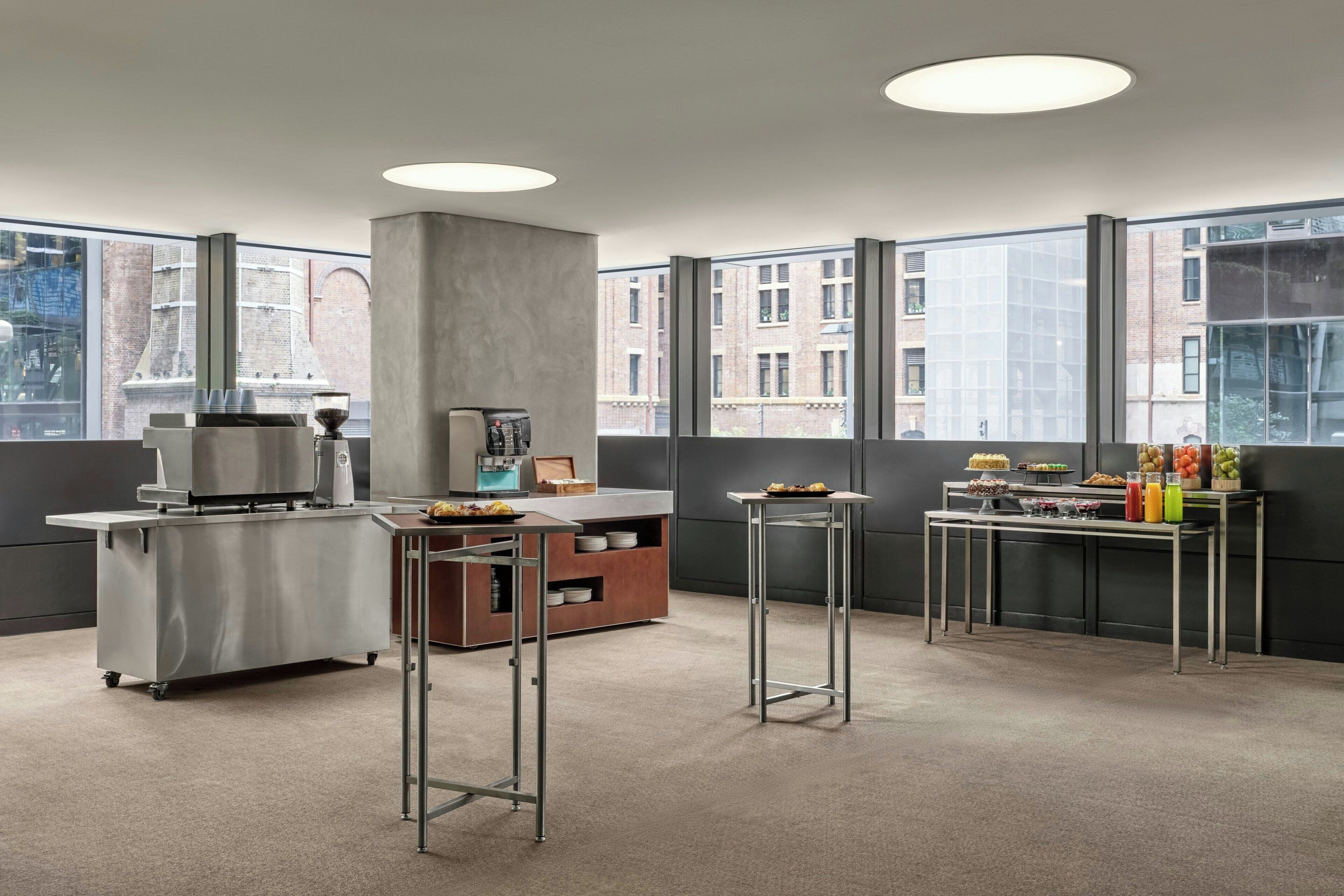 Une cuisine moderne équipée d’appareils électroménagers en acier inoxydable, d’une machine à café et d’une table de buffet où sont disposés des plats et des boissons.