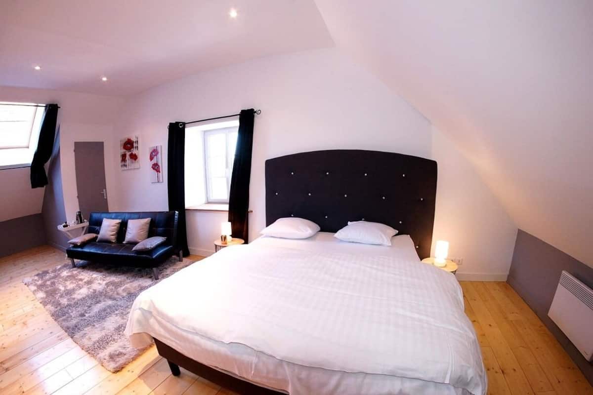 Een slaapkamer met een groot bed, een bank en een raam.