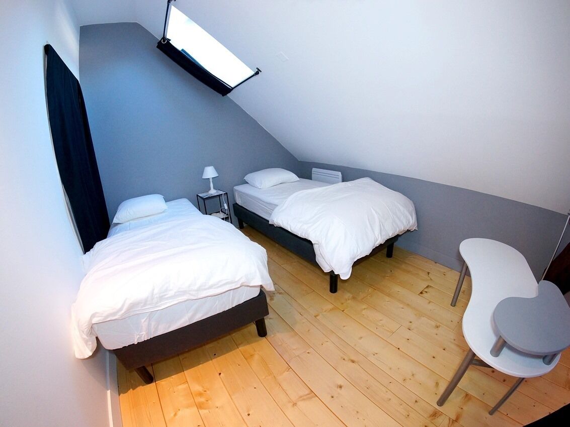 Een slaapkamer met twee bedden, een bureau en een stoel.