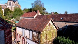 A historic building with a church steeple, surrounded by traditional houses with red-tiled roofs. - La Maison D'hôtes de Toucy (Toucy)