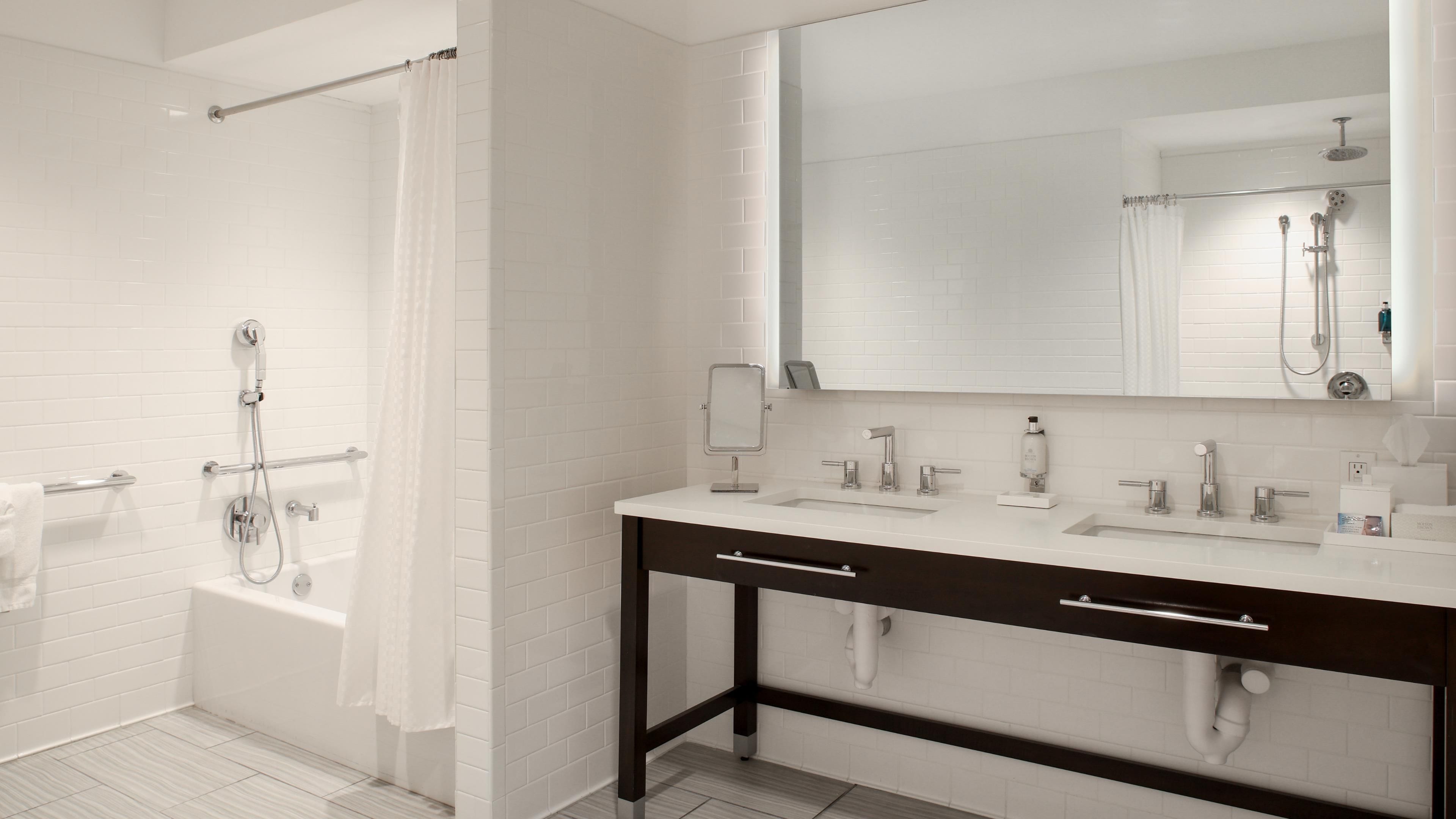 Un baño moderno con ducha a nivel, un espejo grande y un tocador con dos lavabos.