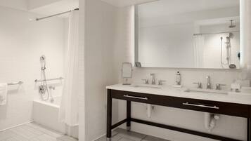 Un baño moderno con ducha a nivel, un espejo grande y un tocador con dos lavabos.