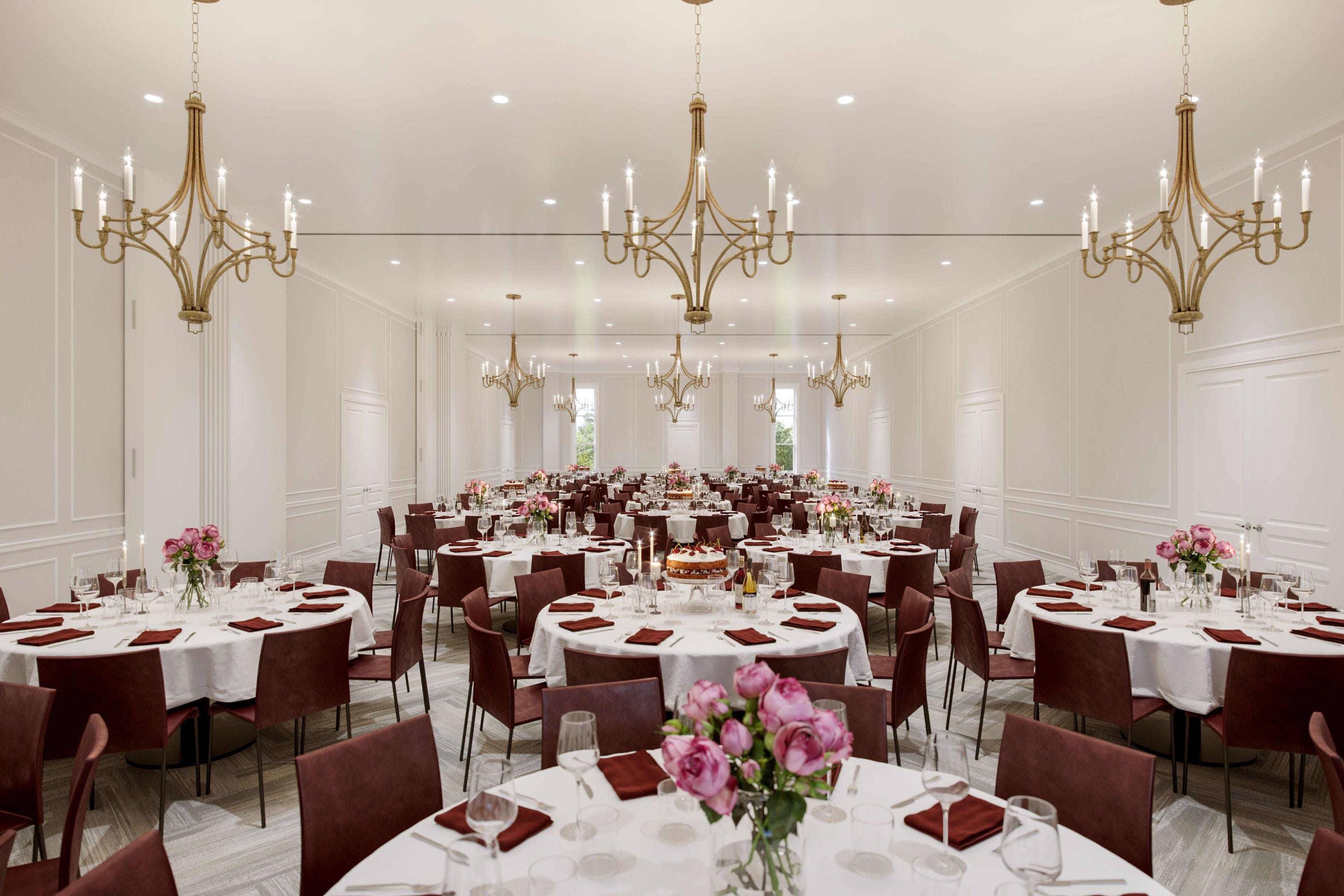 A large banquet hall with round tables set for dining, adorned with white tablecloths and red napkins.