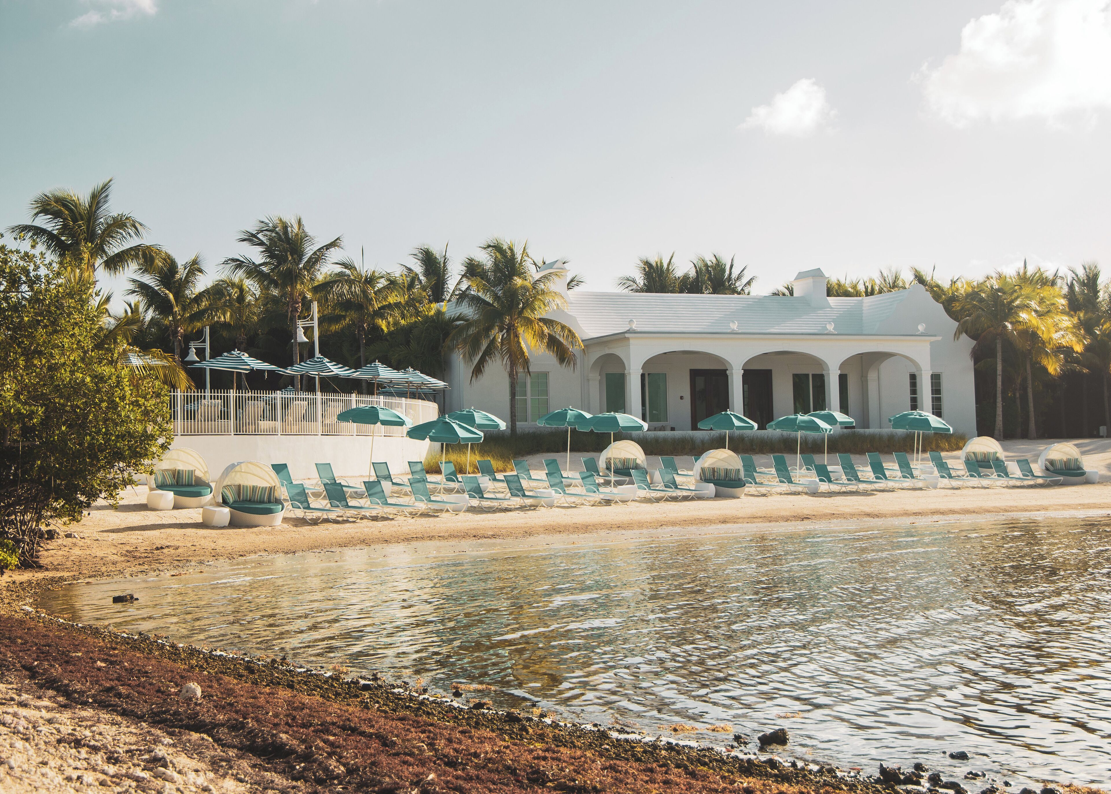 A beachfront hotel with a pool, lounge chairs, and umbrellas.