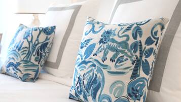 A bed with white bedding and blue patterned pillows.