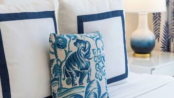 Una cama bien hecha con ropa de cama blanca y almohadas azules y blancas.