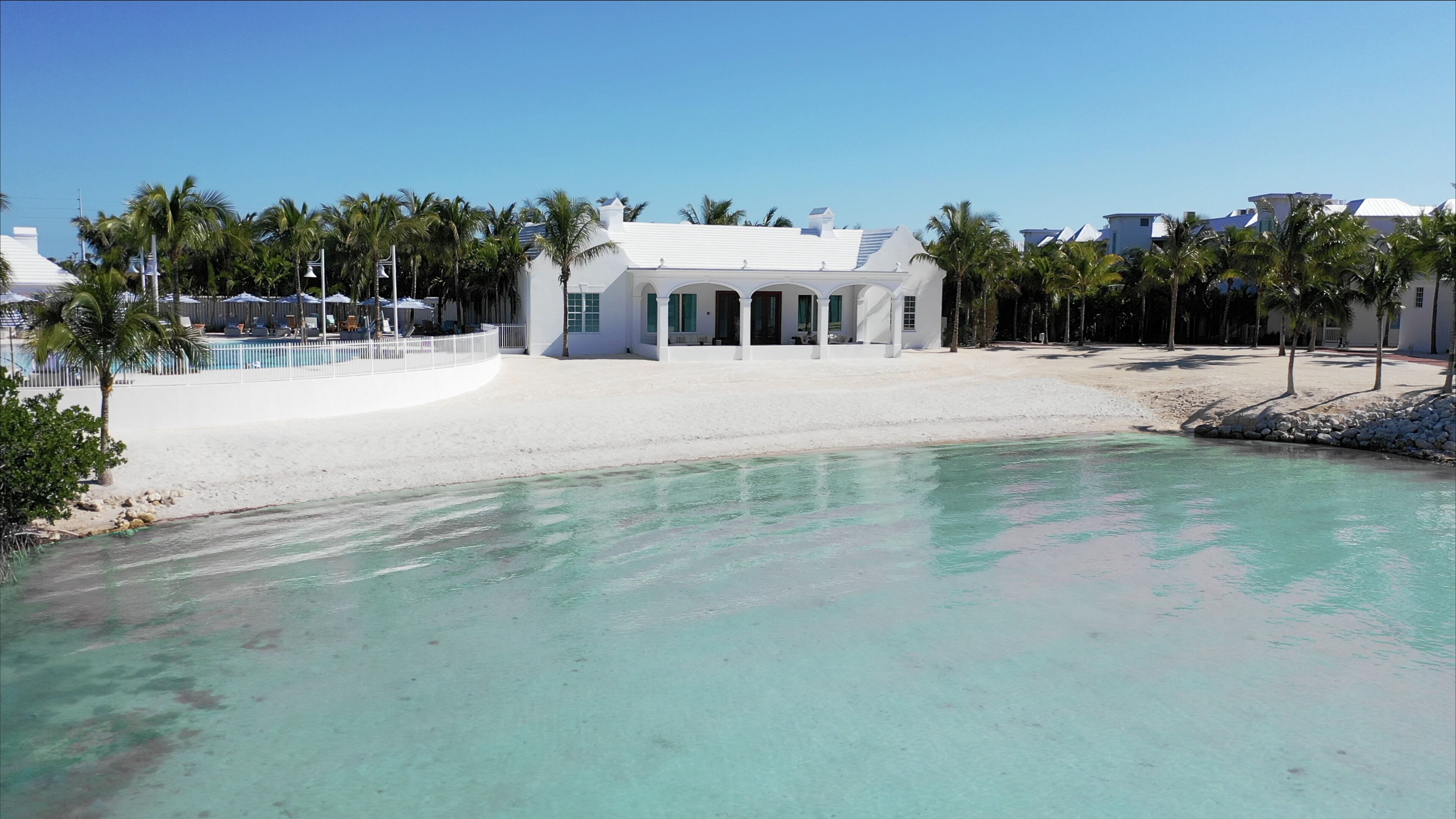 A beachfront property with a pool, white building, and palm trees.