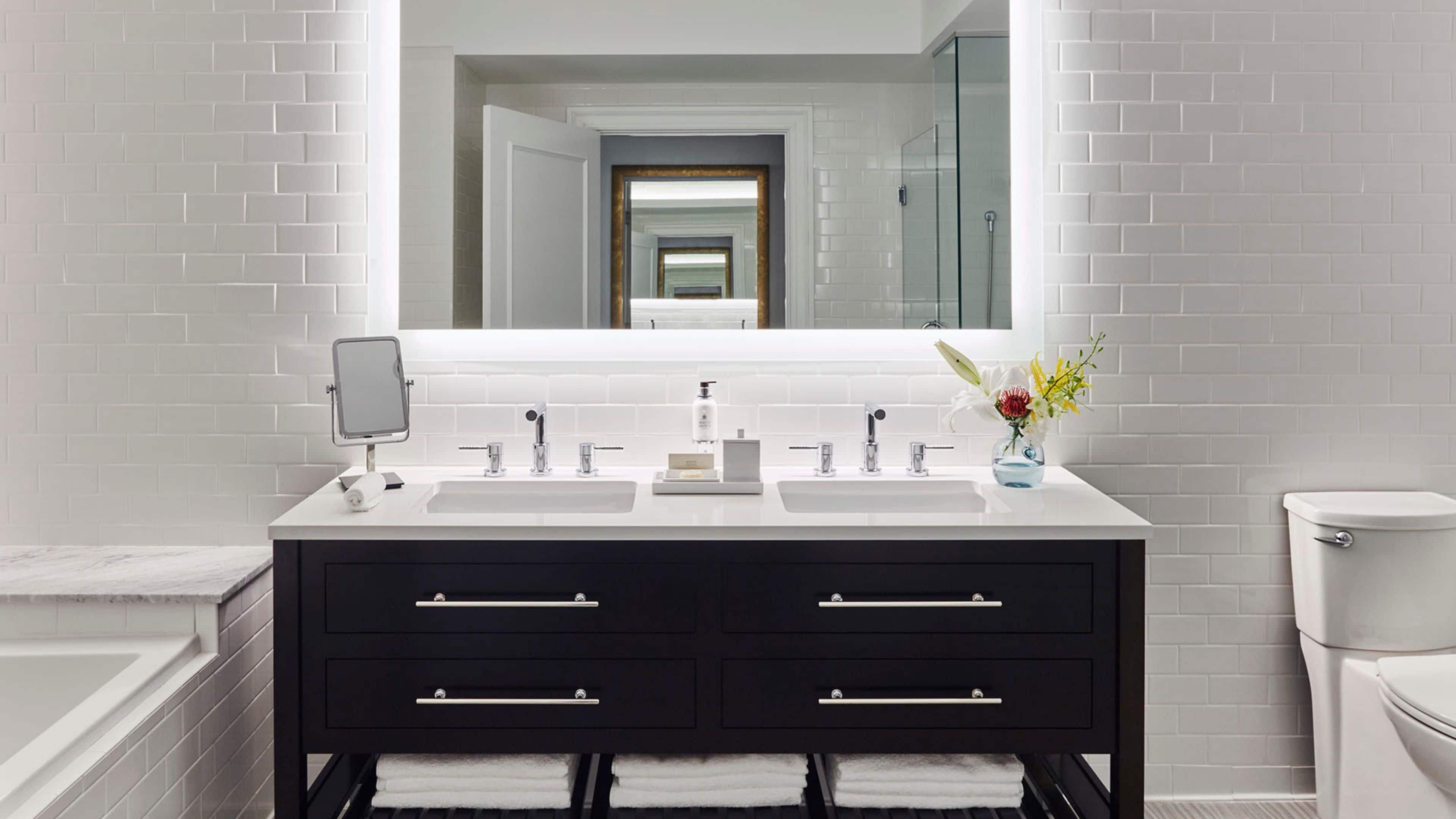 Une salle de bain moderne avec deux lavabos, un grand miroir et des toilettes.