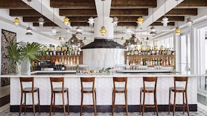 Un espace bar avec des chaises en bois, un comptoir et une variété de bouteilles et de verres.