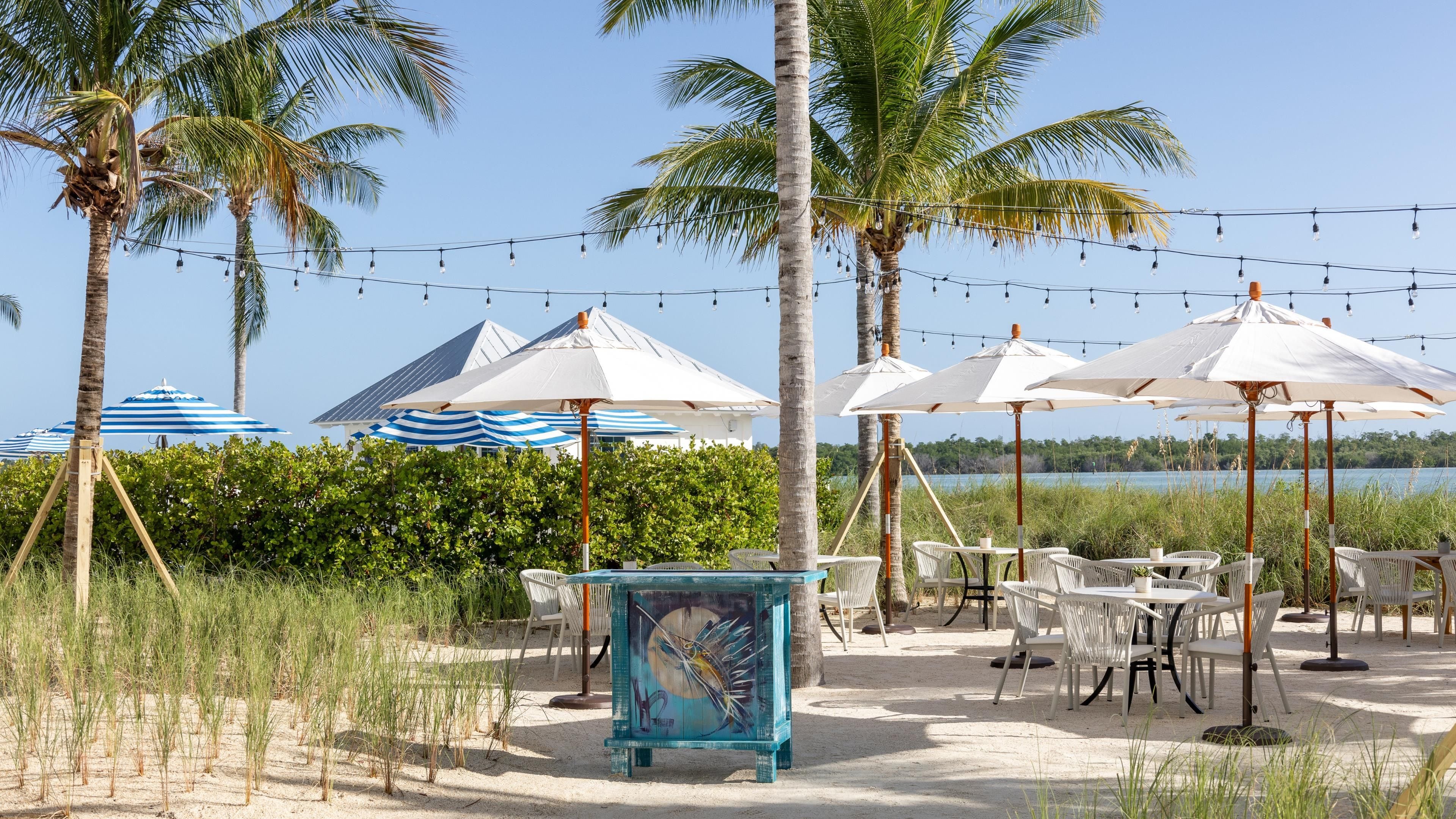 An outdoor seating area with tables and chairs, umbrellas, and string lights.