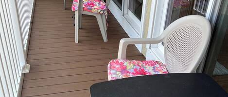 A covered patio with a table and chairs, a sliding glass door, and a white railing.