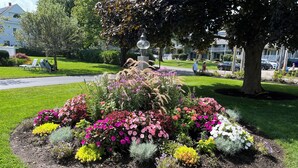 Un jardín ajardinado con una variedad de flores y arbustos coloridos, rodeado de un césped bien cuidado.