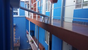 A multi-level building with blue and white exterior walls, a balcony with a metal railing, and a view of the surrounding area. - La Pension Casa Azul - Hostel (Xalapa)