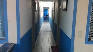 A long, narrow hallway with blue and white walls, tiled floor, and doors on both sides. - La Pension Casa Azul - Hostel (Xalapa)