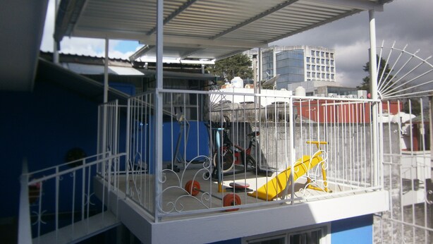 A balcony with a metal railing, a yellow chair, and a white awning. - La Pension Casa Azul - Hostel (Xalapa)