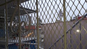A view through a metal fence with a blue building and a large structure in the background. - La Pension Casa Azul - Hostel (Xalapa)