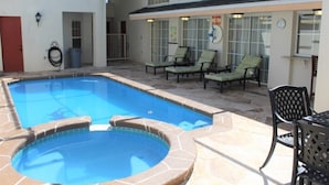 Piscina com espreguiçadeiras e área de estar coberta.