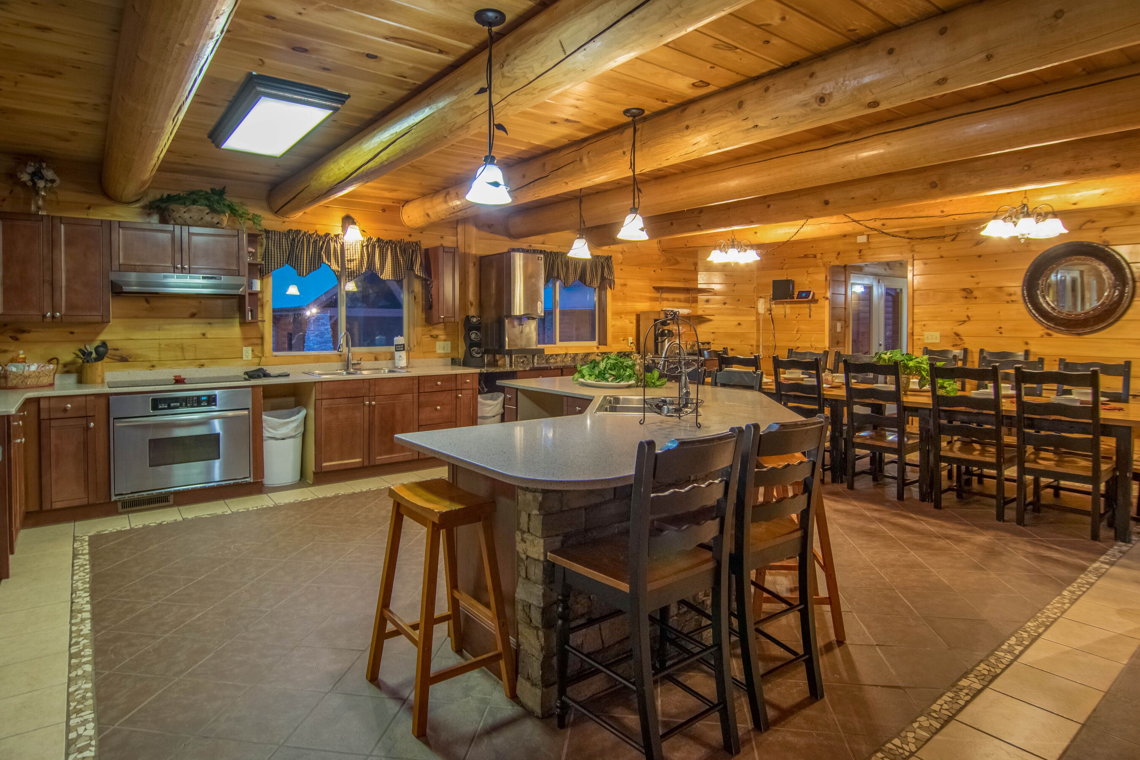 A spacious kitchen with wooden cabinets, a large island with stools, and a dining area with multiple chairs.