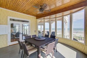 A covered patio with a table and chairs, a ceiling fan, and a view of the beach. - 508 Ocean by AvantStay | Waterfront, Pool, Beach (Isle of Palms)