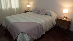 Un dormitorio con una cama, dos mesitas de noche y una mesilla.
