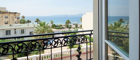 A balcony with a view of the sea, buildings, and palm trees.