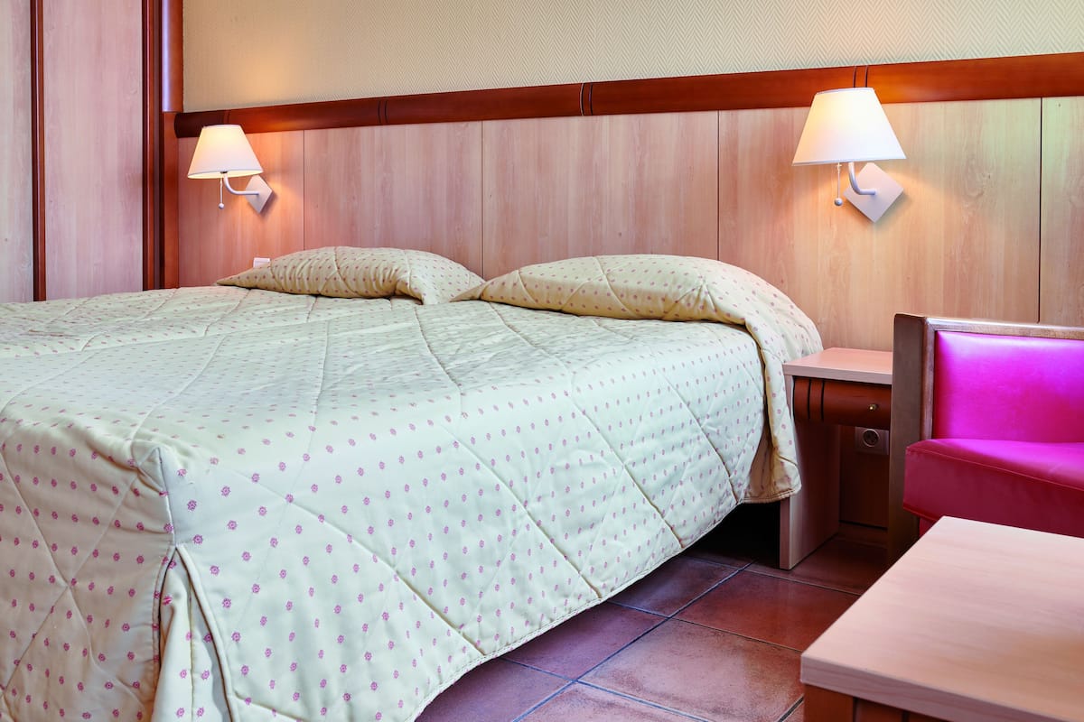 A hotel room with a bed, bedside tables, and a seating area.