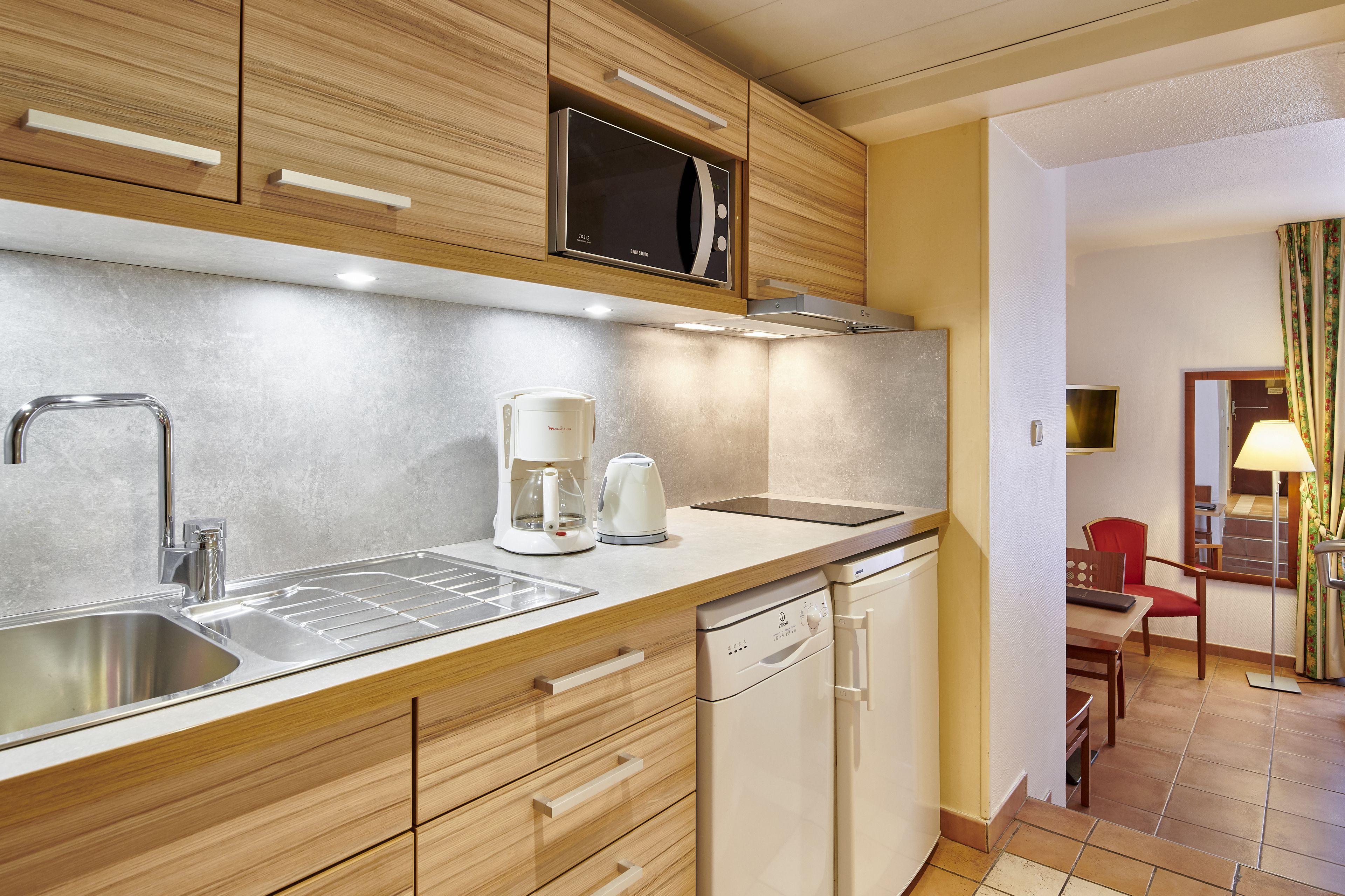 Una cocina moderna con un lavamanos de acero inoxidable, un microondas y una cafetera.