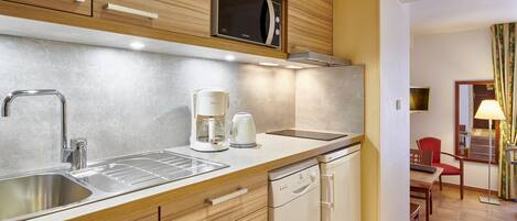 Una cocina moderna con un lavamanos de acero inoxidable, un microondas y una cafetera.