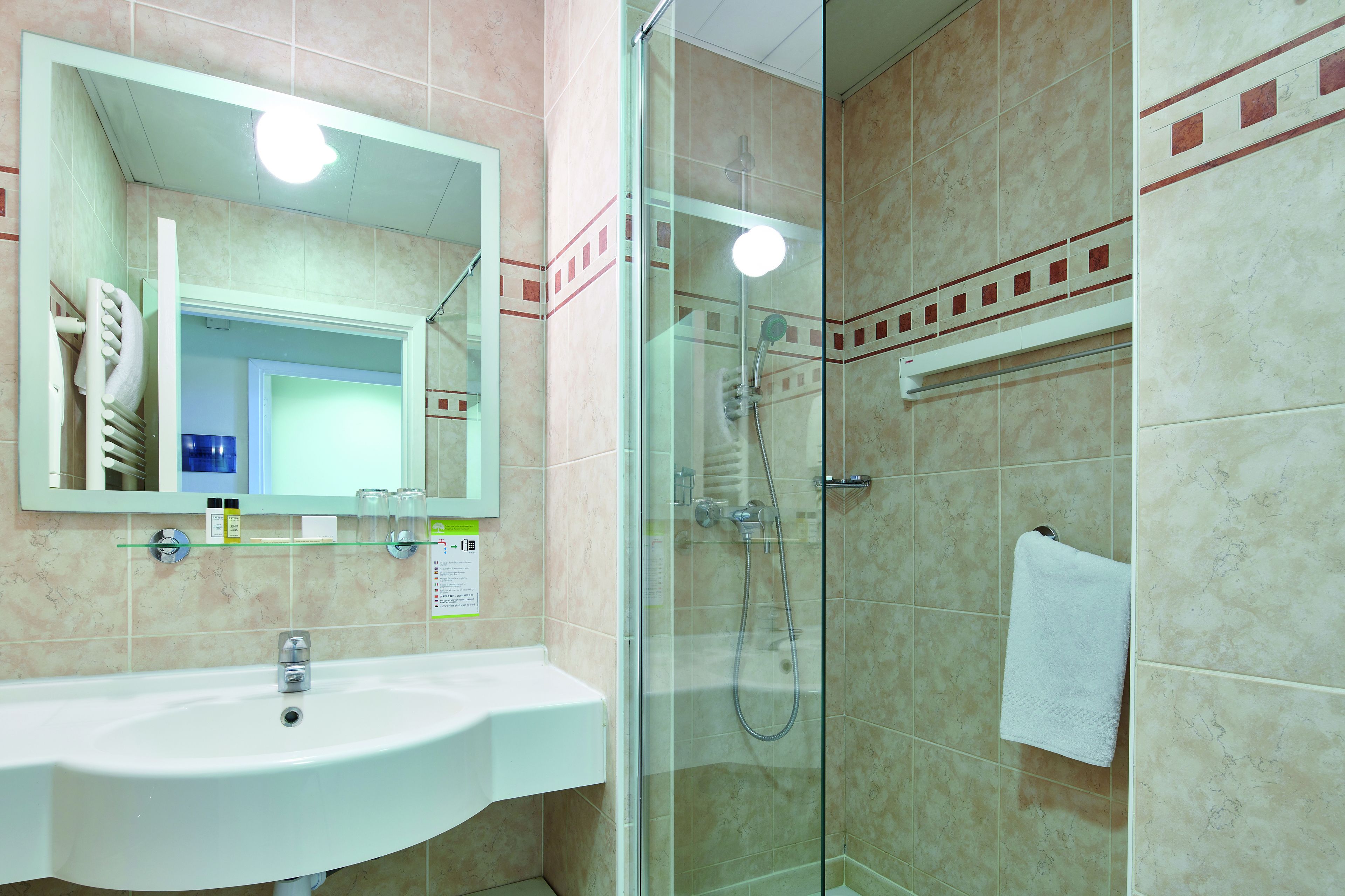 A bathroom with a white sink, a glass shower enclosure, and a towel hanging on the wall.