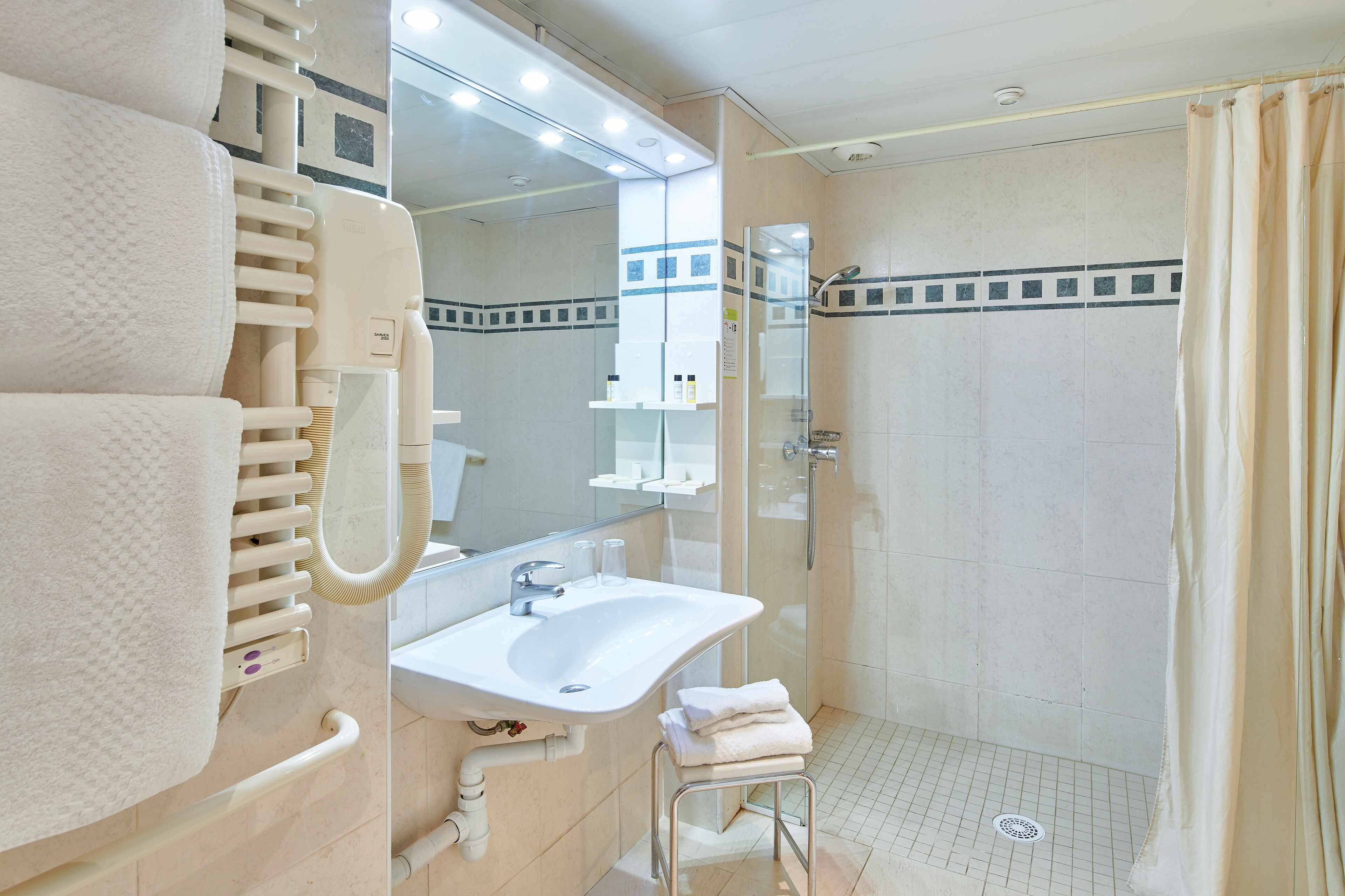 A modern bathroom with a glass-enclosed shower, a white sink, and a towel rack.