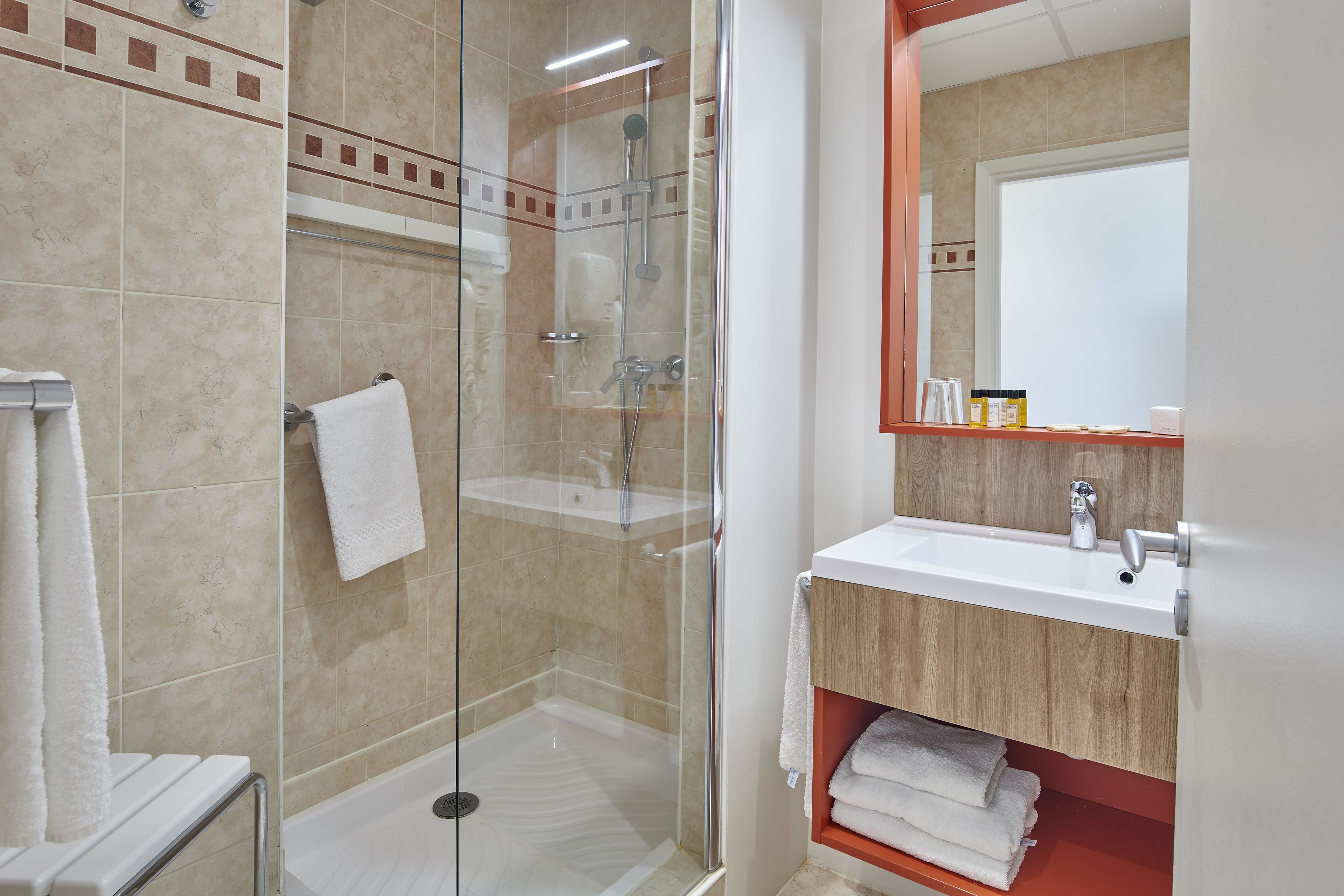 A modern bathroom with a glass-enclosed shower, a white sink, and a wooden vanity.