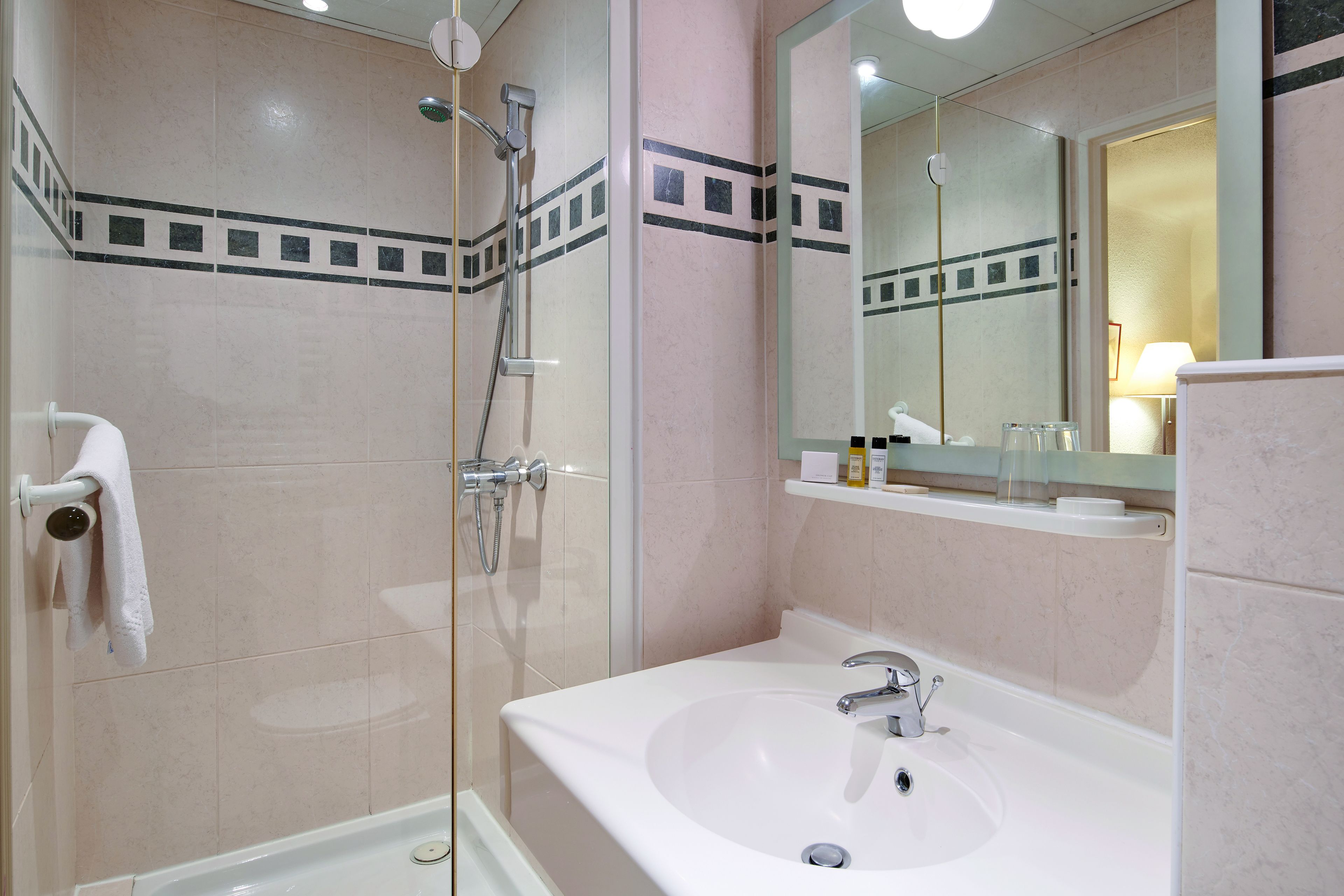 A modern bathroom with a glass-enclosed shower, a white sink, and a large mirror.