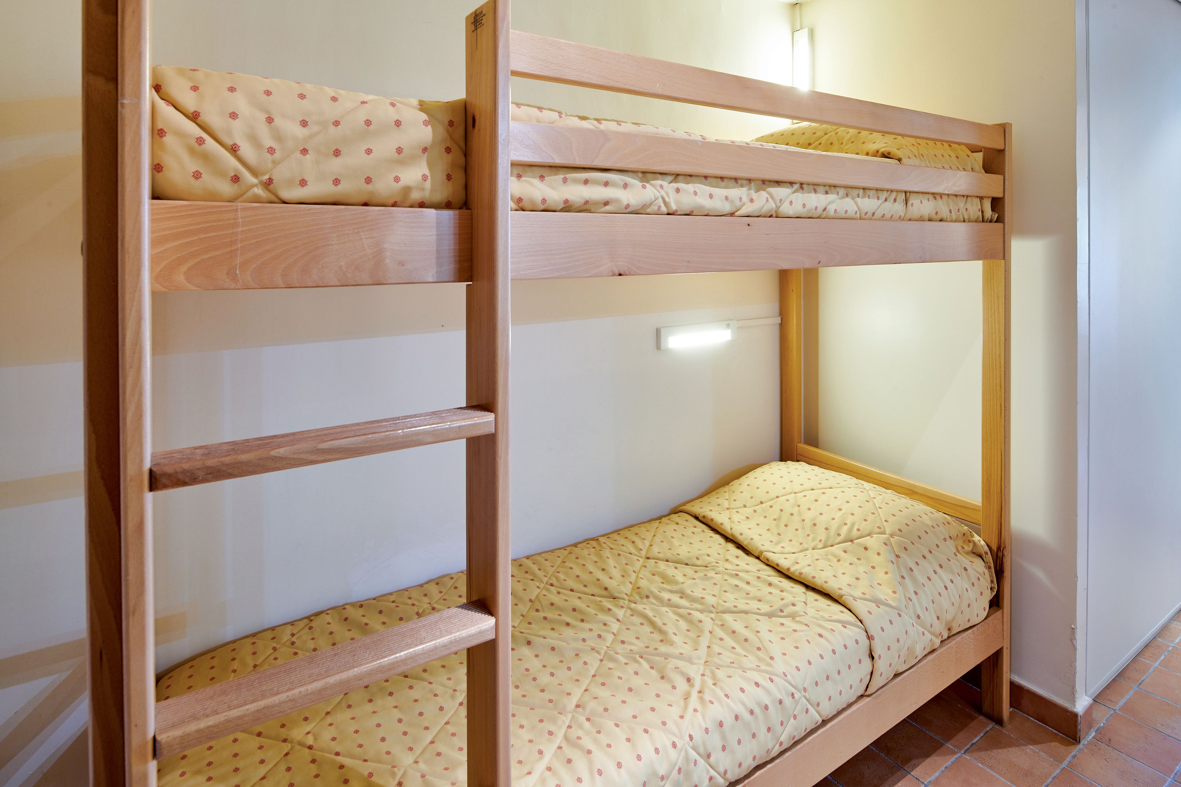 A bunk bed with two levels, each with a wooden frame and a quilted mattress.