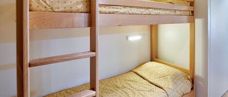 Un lit superposé à deux niveaux, chaque niveau étant doté d’un cadre en bois et d’un matelas matelassé.