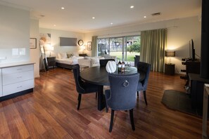 Een moderne woonkamer met een eethoek, een bank, een televisie en een open haard.