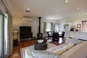 Una sala de estar moderna con un sofá, un televisor de pantalla plana, una chimenea y un comedor con mesa y sillas.
