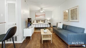 Un salon moderne avec un lit, un canapé bleu, une table basse blanche et une chaise noire.