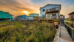 A coastal house with a wooden deck and a balcony, surrounded by vegetation. - FRONT ROW SEATS TO THE GULF OF Mexico! There's No Better View  TOTAL RENOVATION (Freeport)