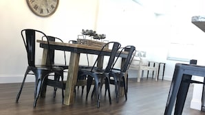 Un coin repas avec une table en bois et des chaises noires, une horloge murale et un lustre.