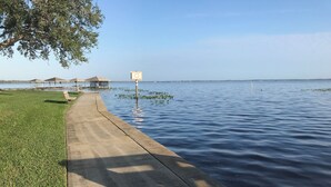 Une promenade en bord de mer avec un chemin en béton, des espaces verts et un panneau indiquant l’emplacement d’une zone de mise à l’eau pour les bateaux.