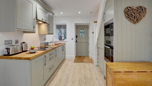 A modern kitchen with grey cabinets, a wooden countertop, and a heart-shaped decoration on the wall. - 2 Bed in Lynmouth (oc-foxcot) (Lynmouth)