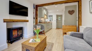 A modern living room with a fireplace, a grey sofa, and a wooden coffee table with a magazine. - 2 Bed in Lynmouth (oc-foxcot) (Lynmouth)