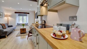 A modern kitchen with a wooden countertop, a dining area with a sofa, and a window with a view. - 2 Bed in Lynmouth (oc-foxcot) (Lynmouth)